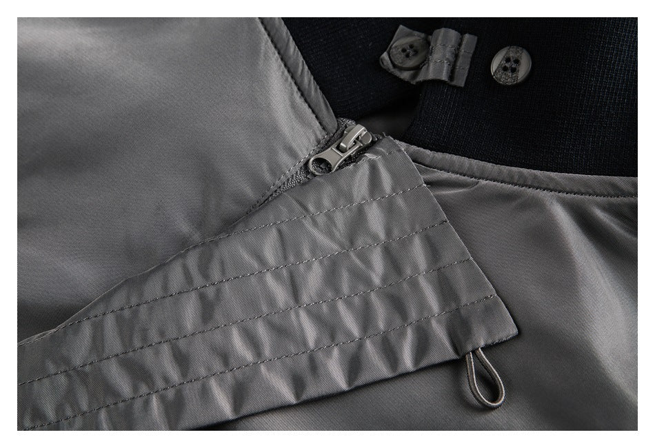 Close-up of a gray garment's zipper and button fastening against a black section.