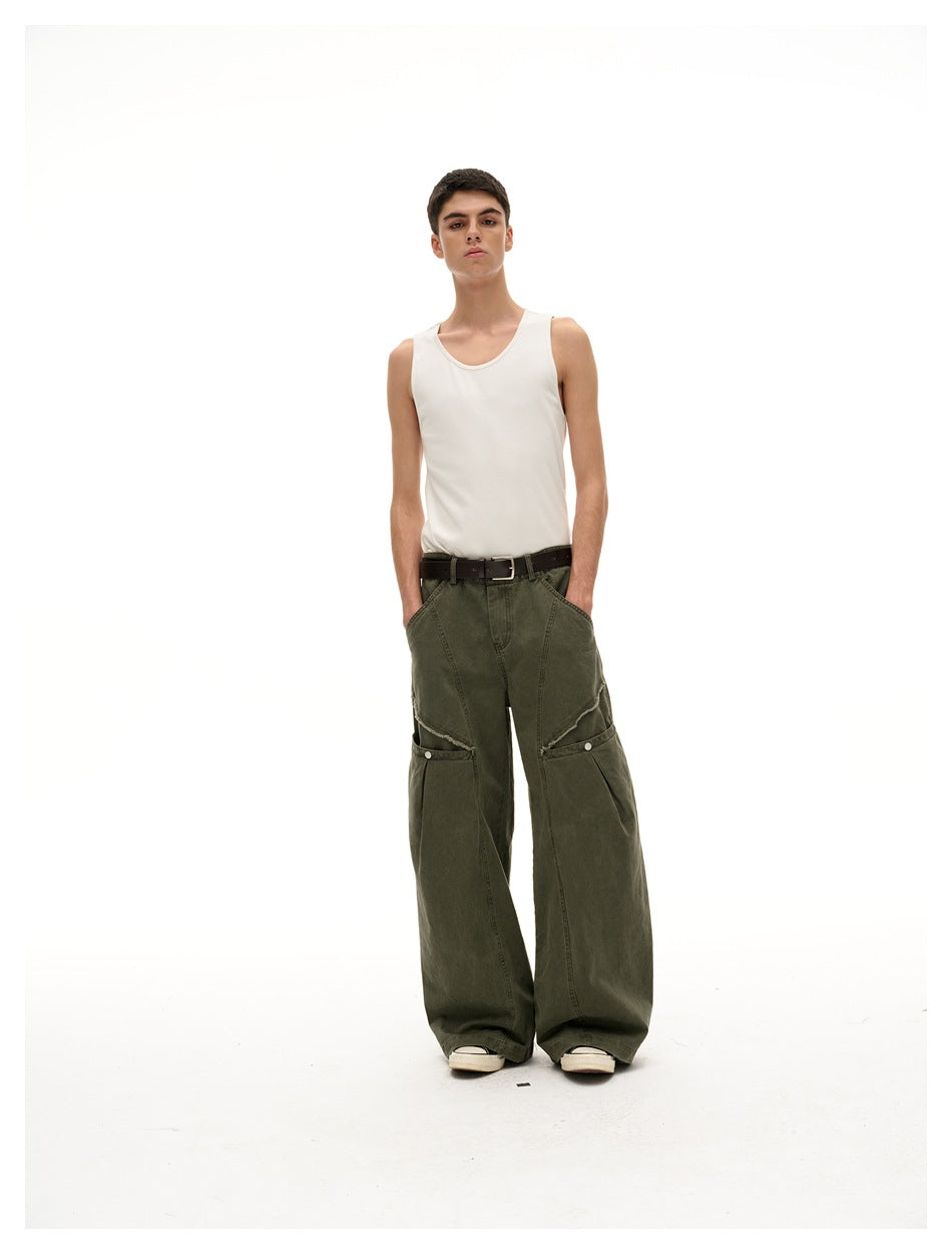 Model wearing dark olive wide-leg pants with layered knee panels and a white tank top, front view.