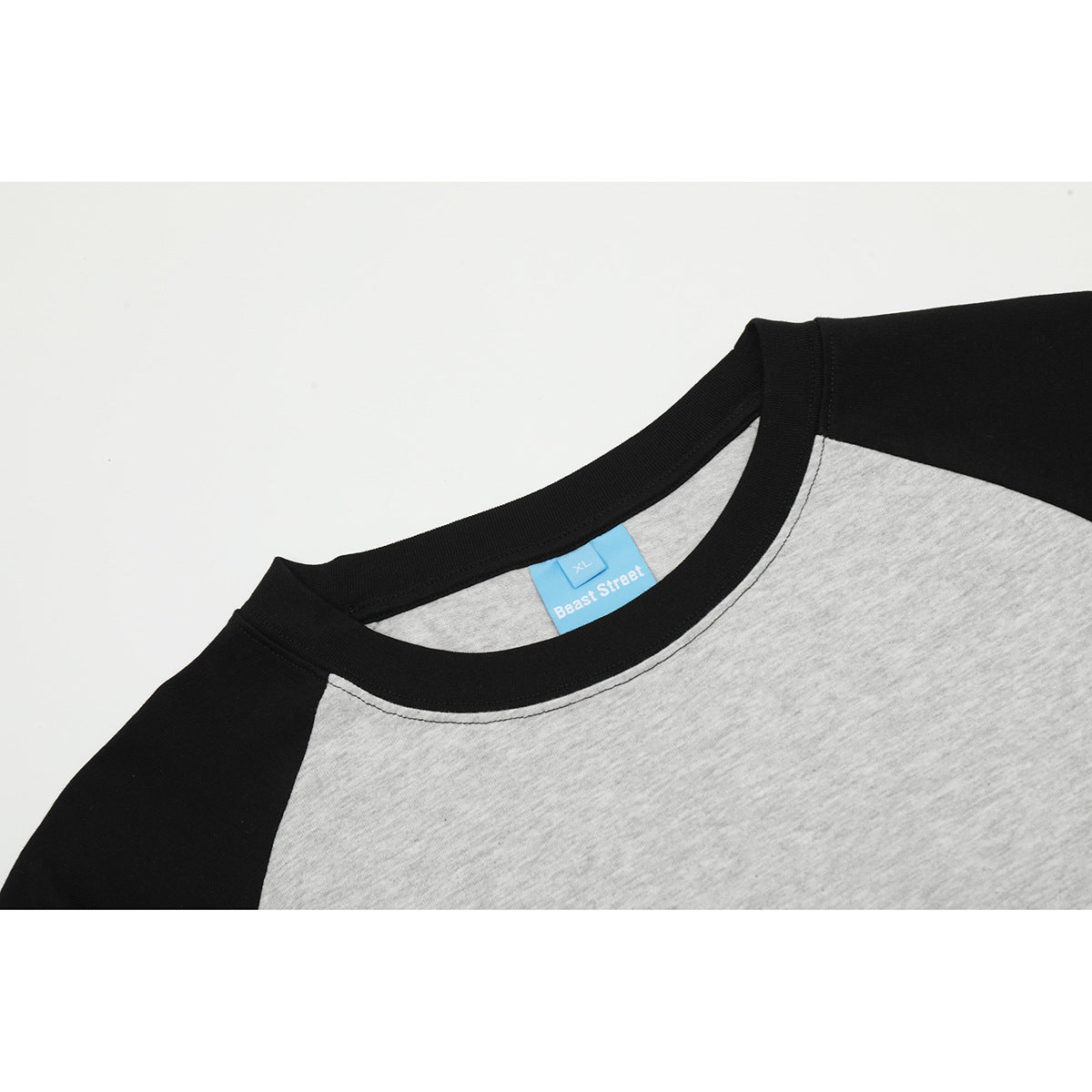 Close-up of a gray raglan T-shirt neckline with black collar and sleeves and a blue Beast Street size label.