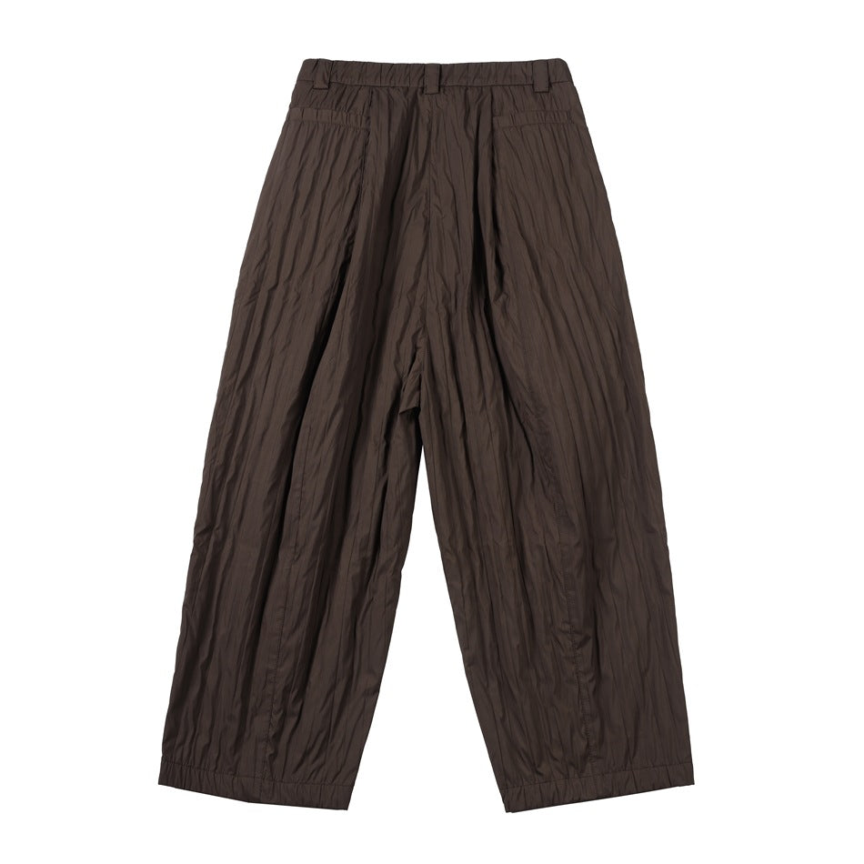 Back view of brown wide-leg pants with crinkled texture, belt loops and two welt-style back pockets, flat lay