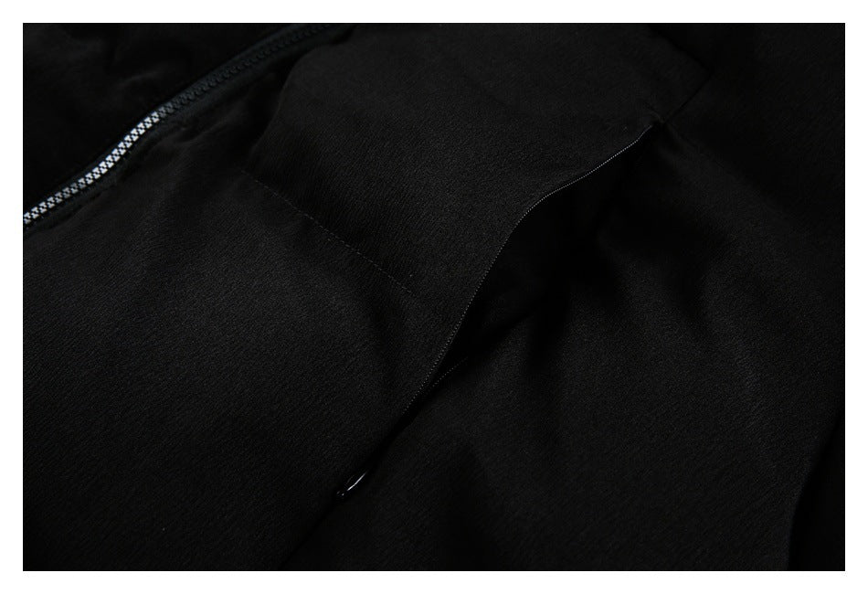 Close-up of black garment showing a zipper and a curved pocket opening.