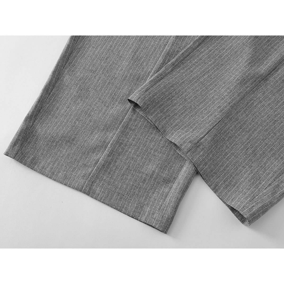 Close-up of the hems and seams of gray pinstripe wide-leg trousers.