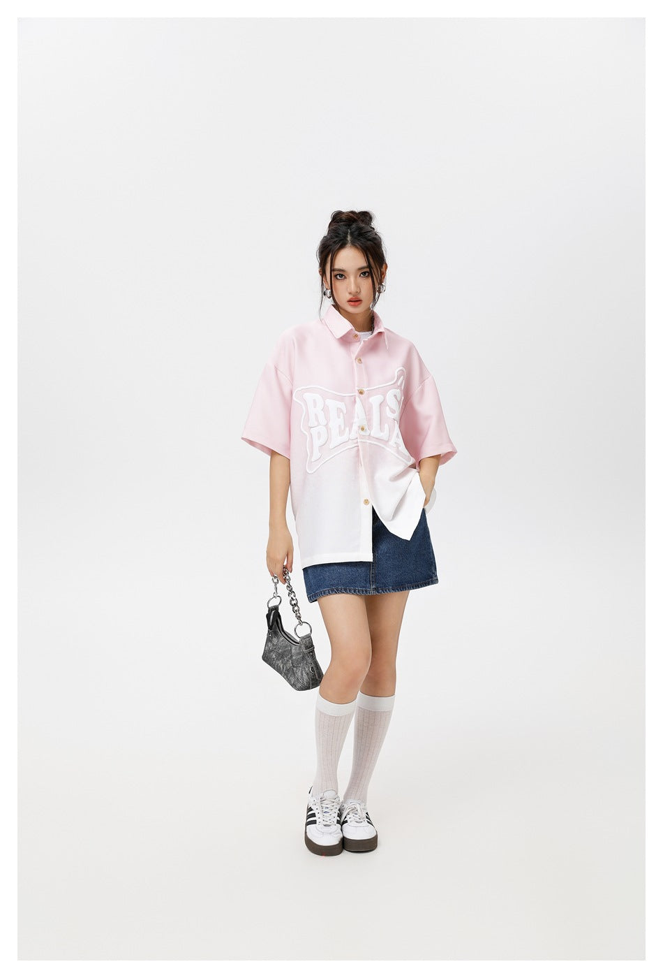 Model in a pink-to-white gradient short-sleeve shirt with raised white lettering, denim mini skirt, socks and sneakers