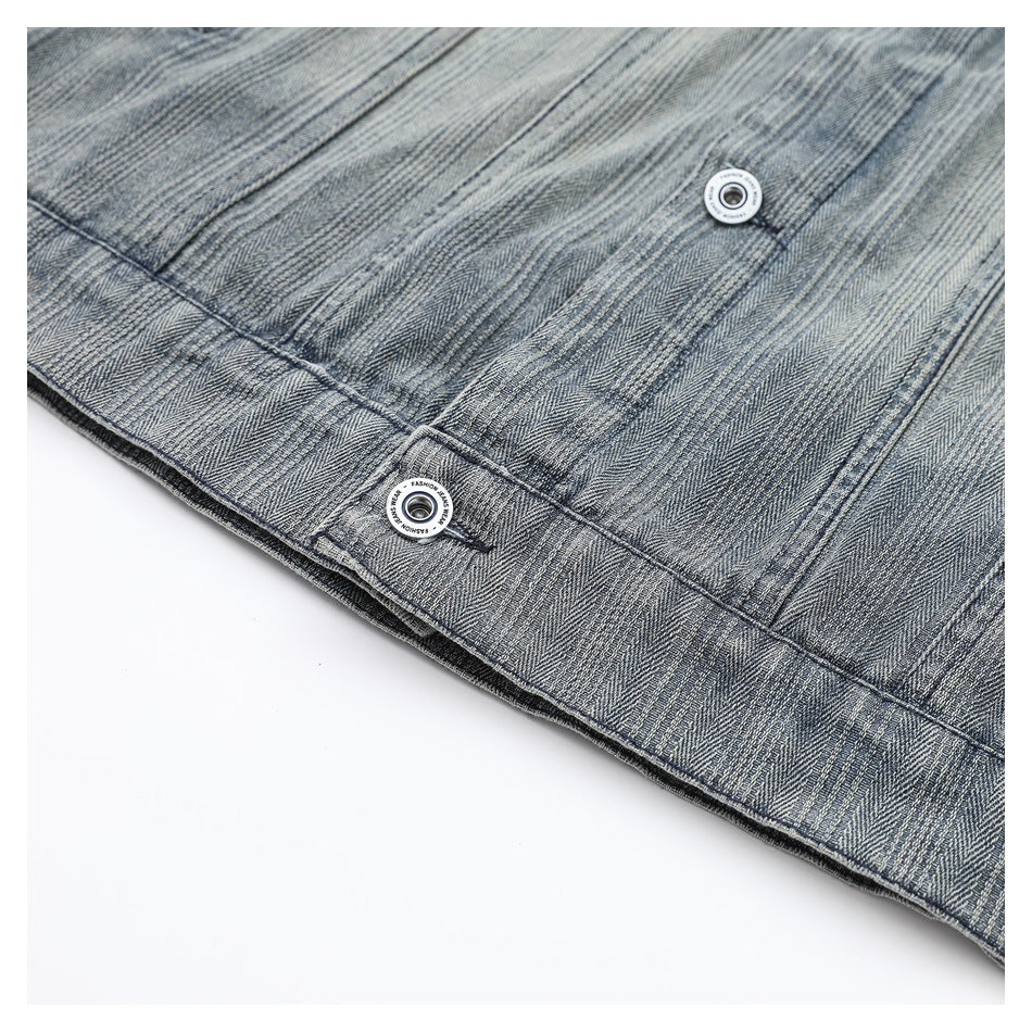 Close-up of gray-blue striped jacket fabric with two round metal snap buttons along a seam.