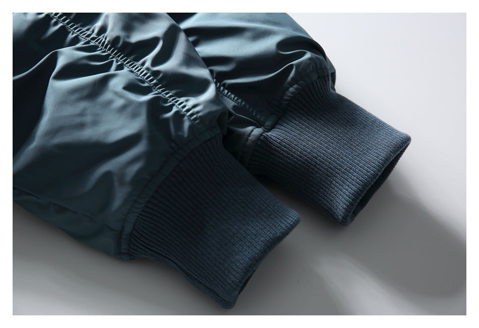Close-up of two blue-gray jacket sleeves with dark ribbed cuffs and gathered stitching.