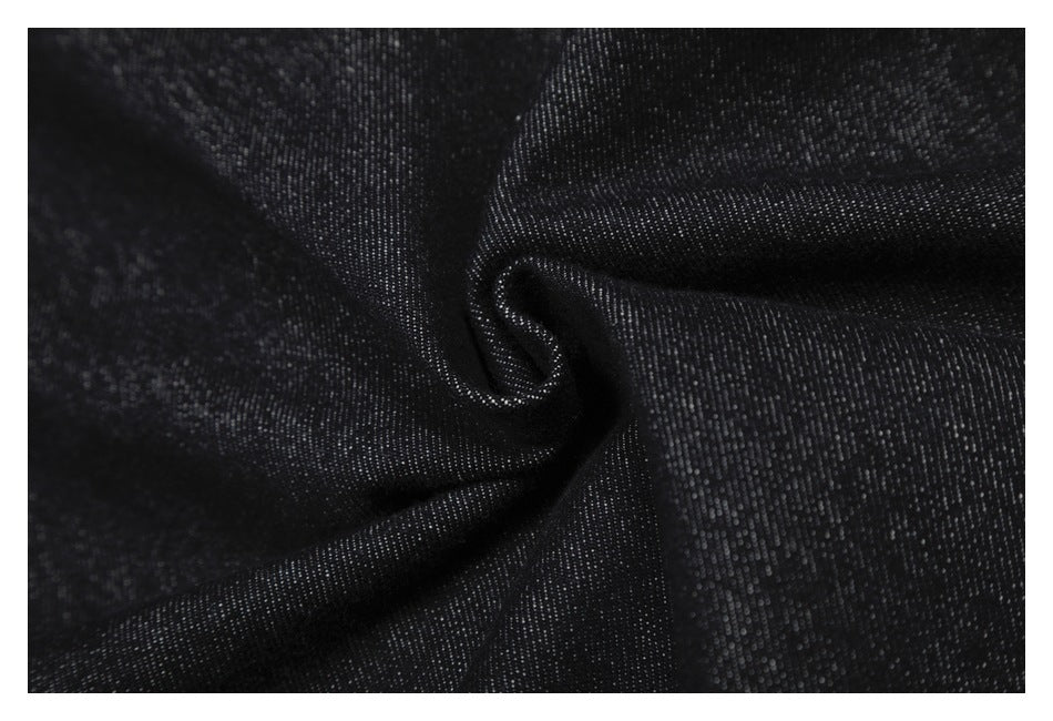 Macro view of dark indigo denim fabric gathered into a fold, showing its woven texture.