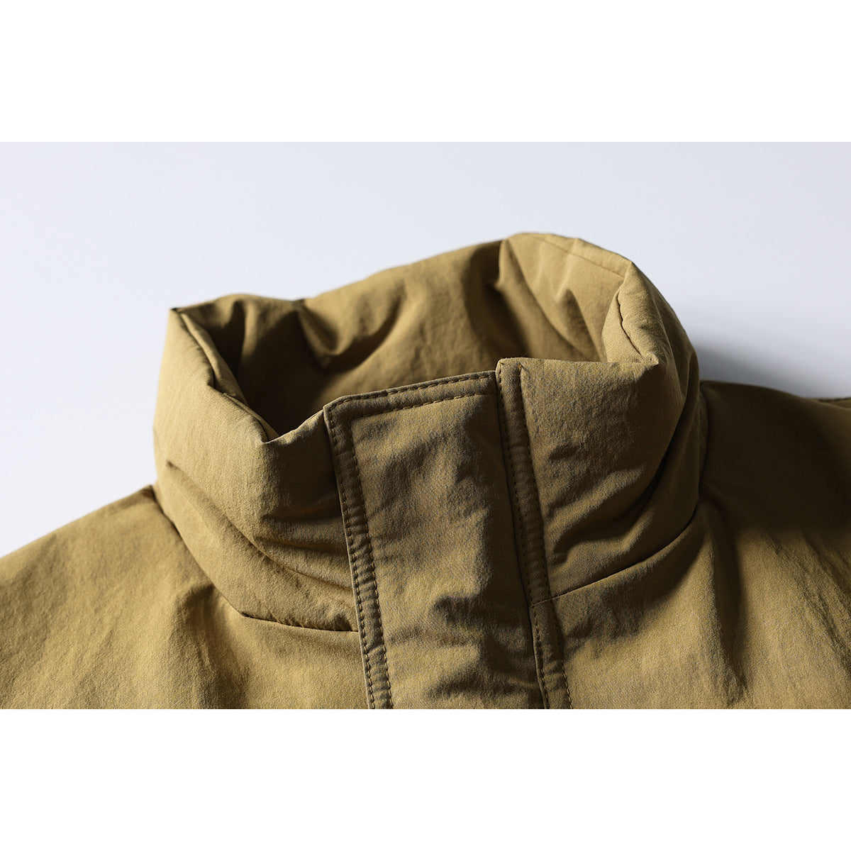 Close-up of a tan jacket's tall stand collar and snap storm flap.