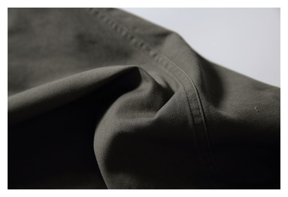 Macro view of dark olive pants showing folded fabric and close-up stitching along a seam.