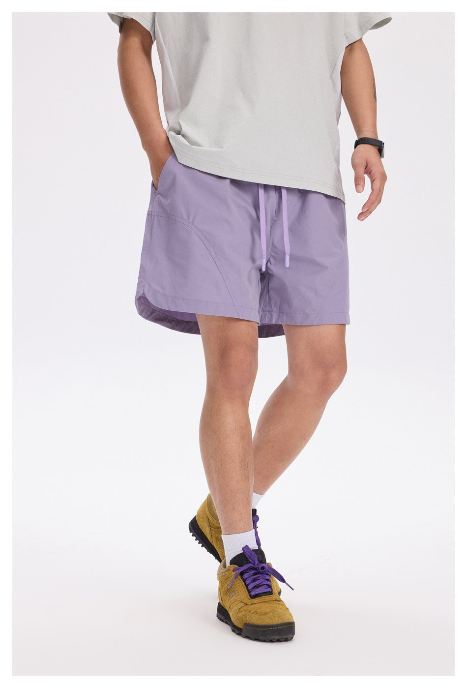 Angled front view of a person wearing lavender drawstring shorts with curved pocket seams.