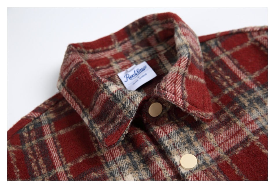 Close-up of the red tartan shirt jacket collar, branded neck label, and cream snap buttons.