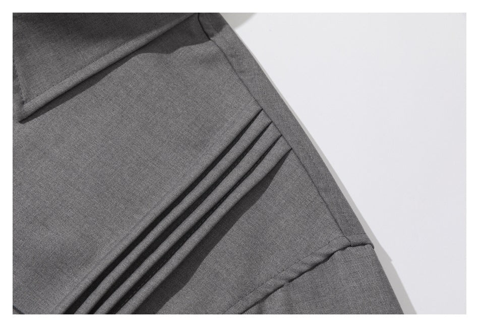 Close-up of parallel pleats and seam construction on a gray shirt.