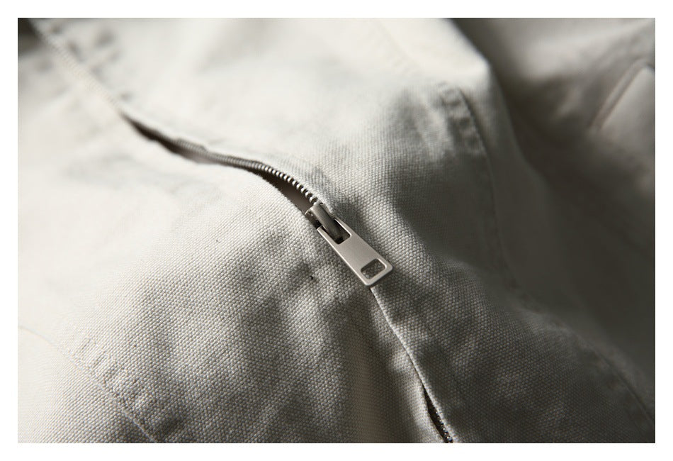 Close-up of a silver zipper on textured light beige garment fabric.