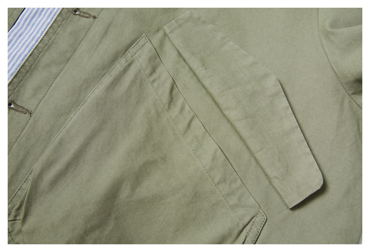Close-up of an olive-green shirt pocket and sleeve, with a small section of its blue-and-white striped placket visible.