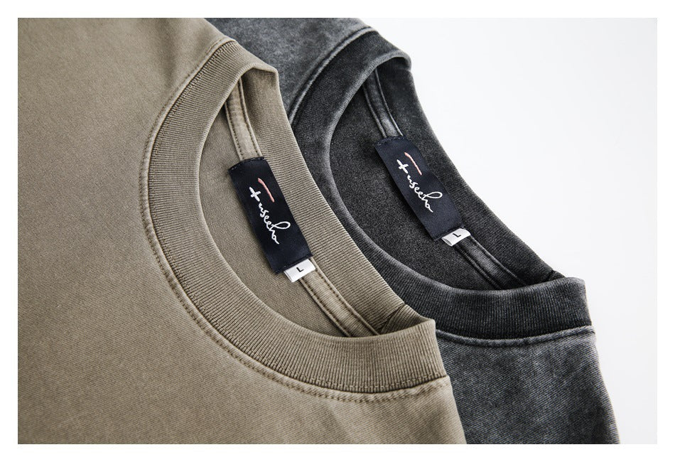 Close-up of the ribbed necklines and sewn-in labels of olive and charcoal T-shirts.