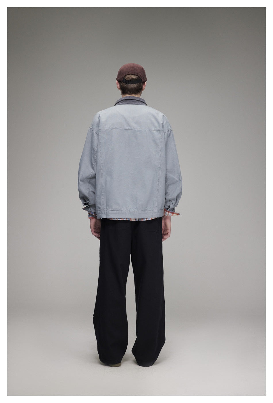 Full-length back view of a model wearing a light gray jacket with a dark collar and black wide-leg pants.