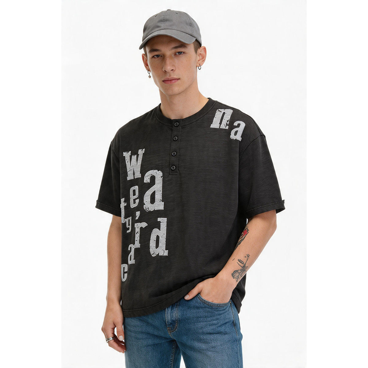 Man in a dark gray henley tee with light gray distressed letter print, gray cap and blue jeans