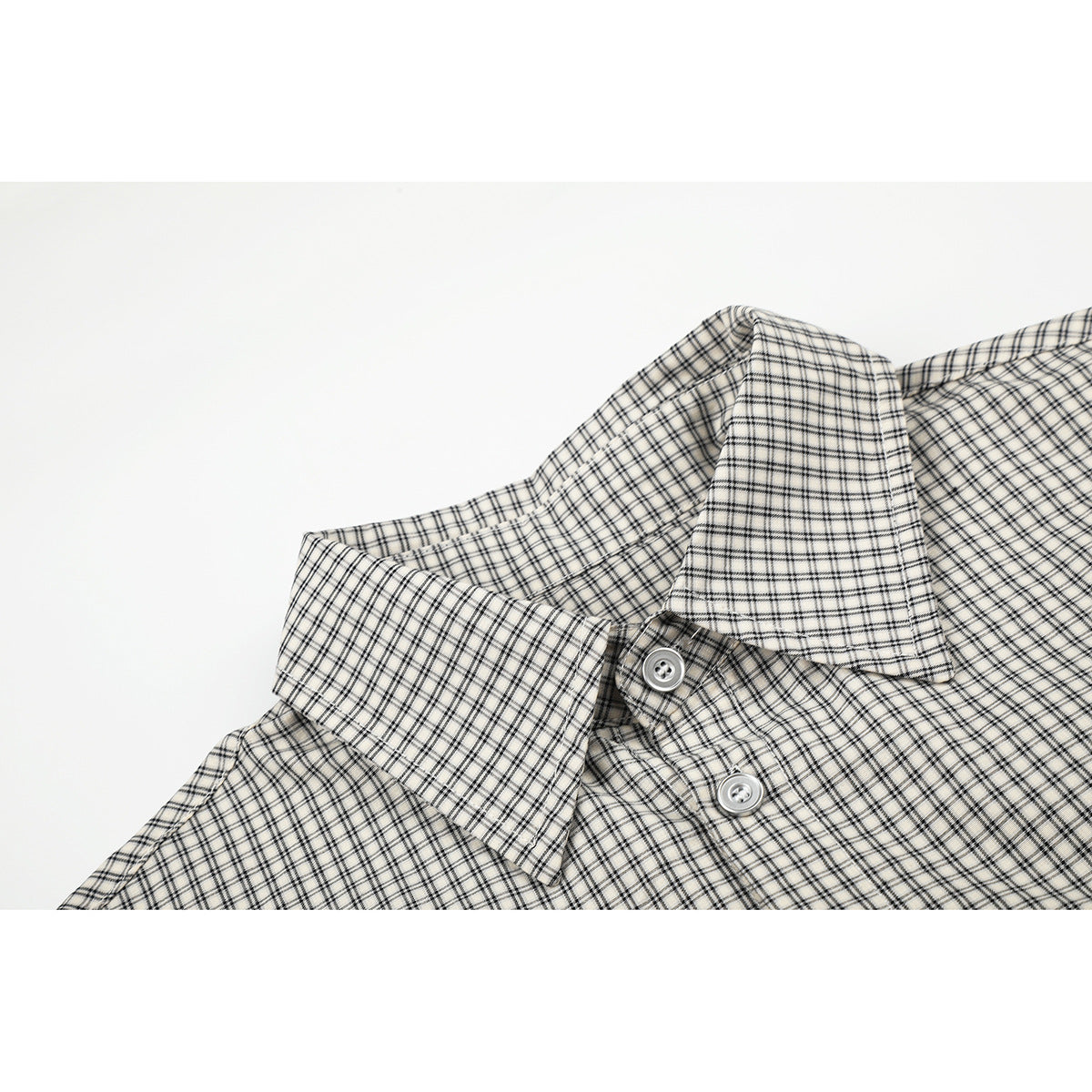 Close-up of a light beige checked shirt collar and upper placket with two white buttons.