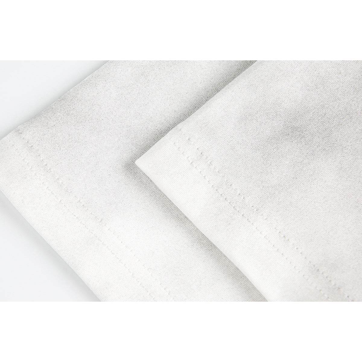 Close-up of light-colored T-shirt fabric and parallel stitched seams.