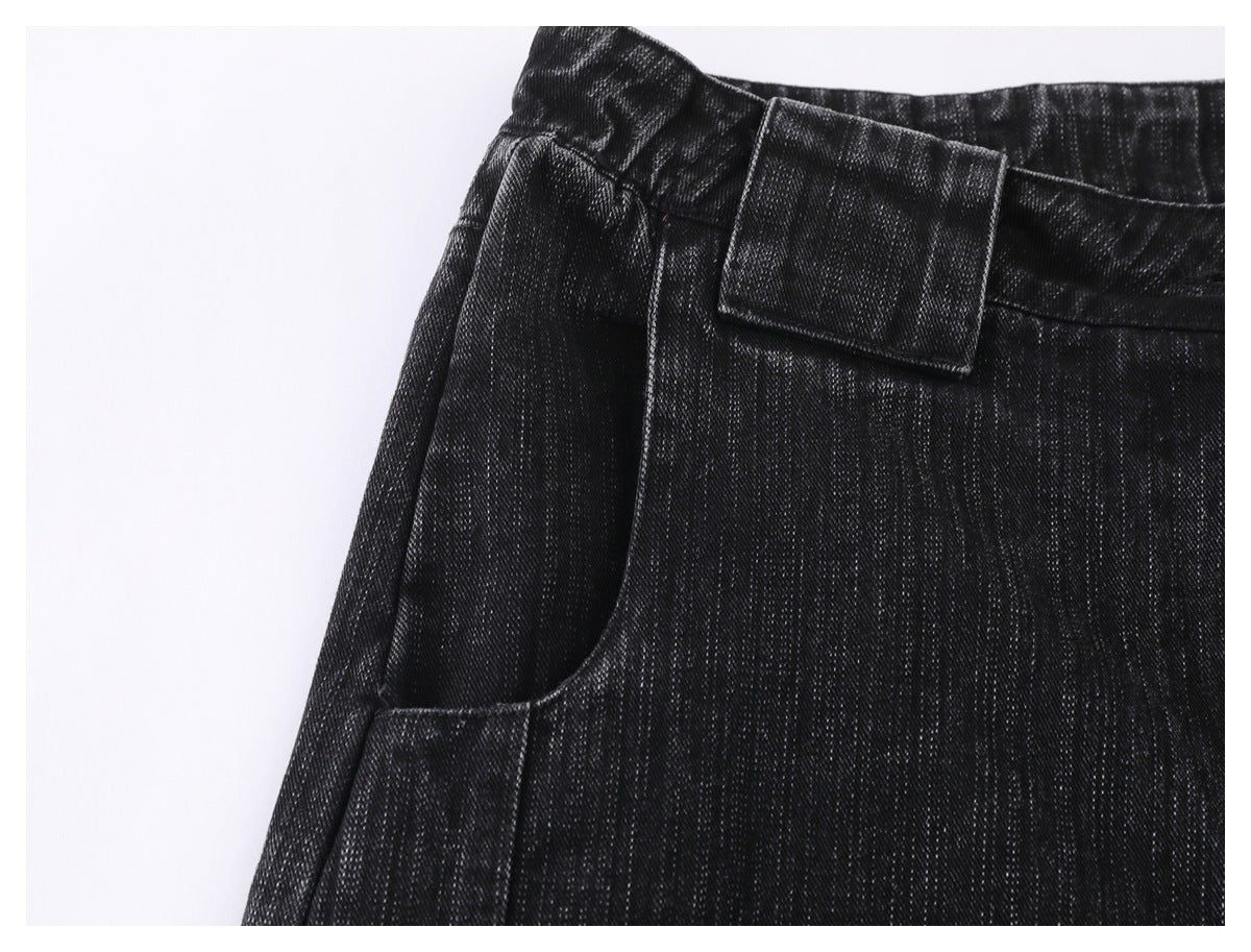Close-up of black denim trousers showing a curved front pocket and belt loop.