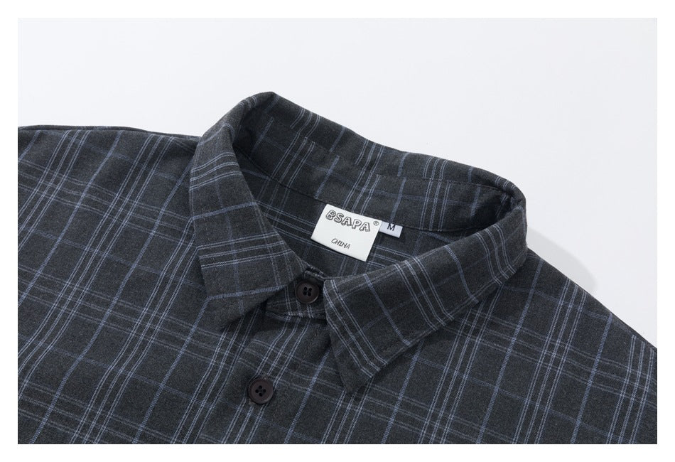 Close-up of a charcoal plaid button-up shirt showing its pointed collar, buttons, and neck label.