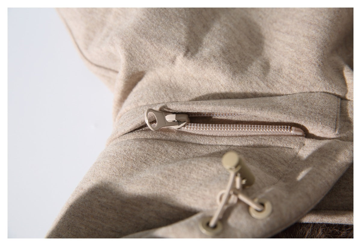 Close-up of the beige jacket's zipper pocket and hood drawcord toggle.