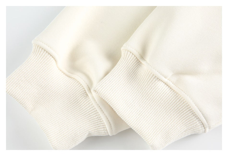 Close-up of the cream sweatshirt's wide ribbed cuffs and stitched sleeve seams.