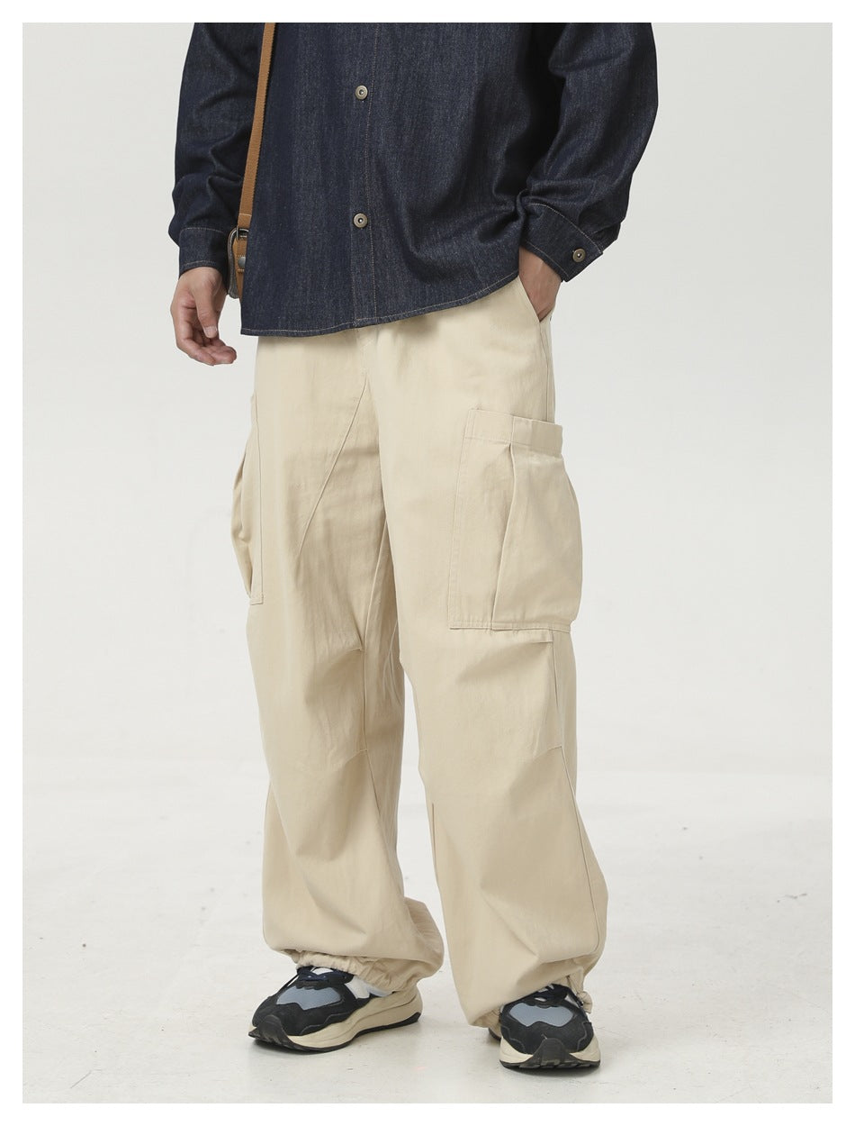 Model wearing loose cream cargo pants with large side pockets and elastic ankle cuffs, shown from the front.