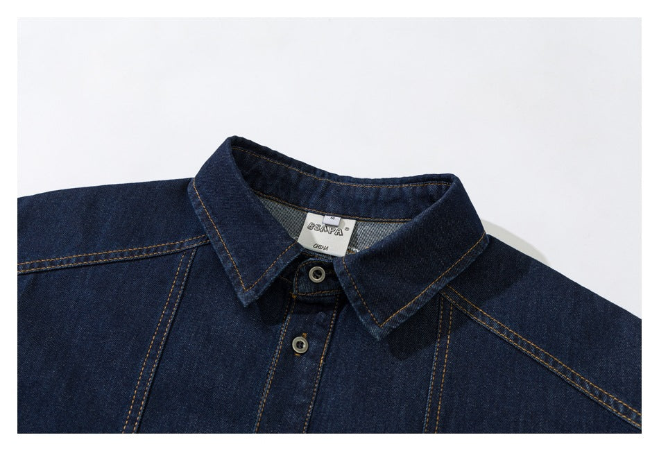 Close view of a dark indigo denim shirt collar and upper button placket with contrast stitching.