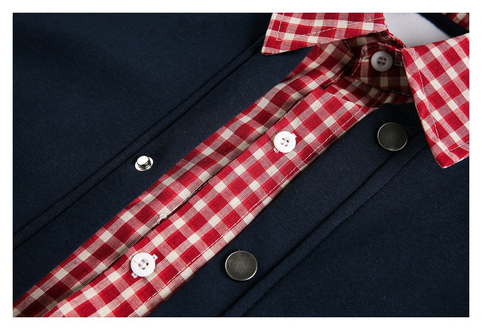 Close-up of the red-and-cream checked placket, white buttons, and dark metal snaps on a navy garment.