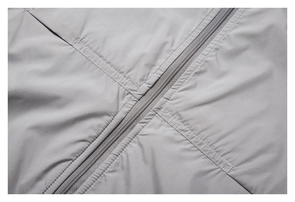 Close-up of a zipper and stitched seams on light gray jacket fabric.