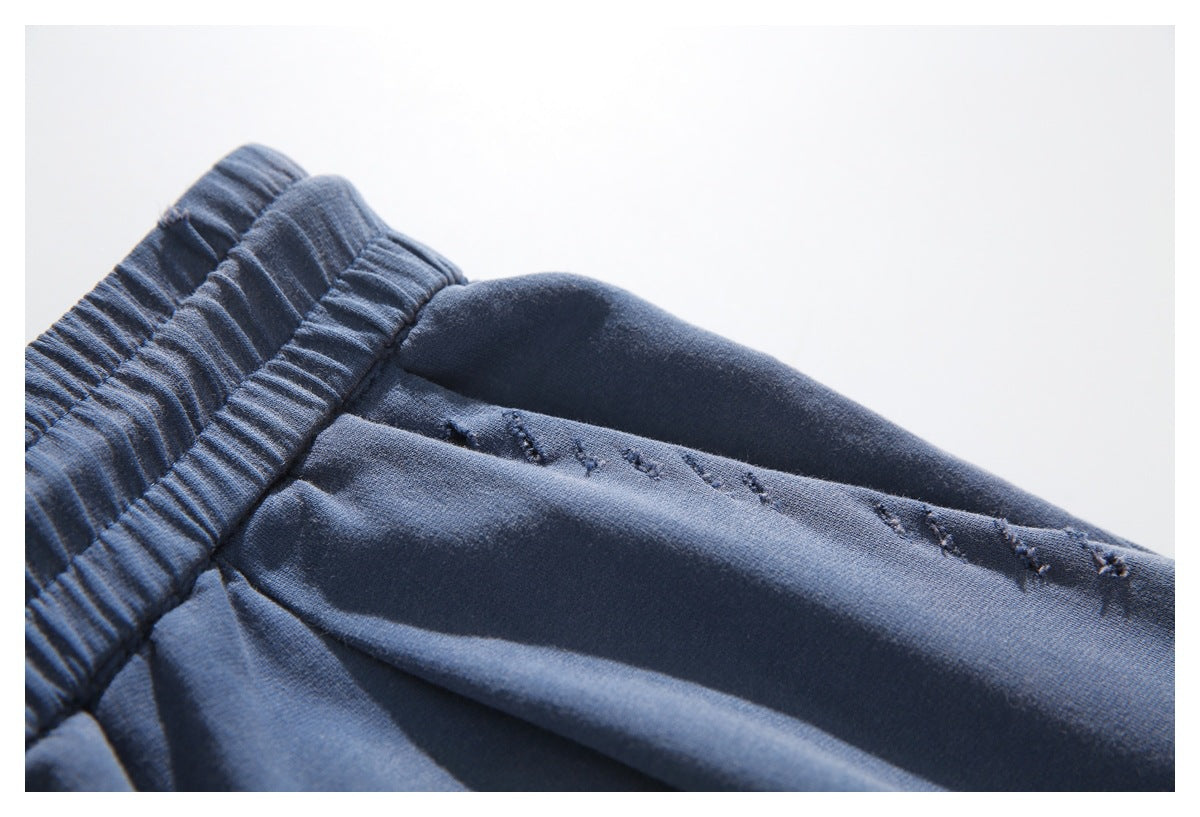 Close-up of navy pants showing the elastic waistband and stitched side seam.