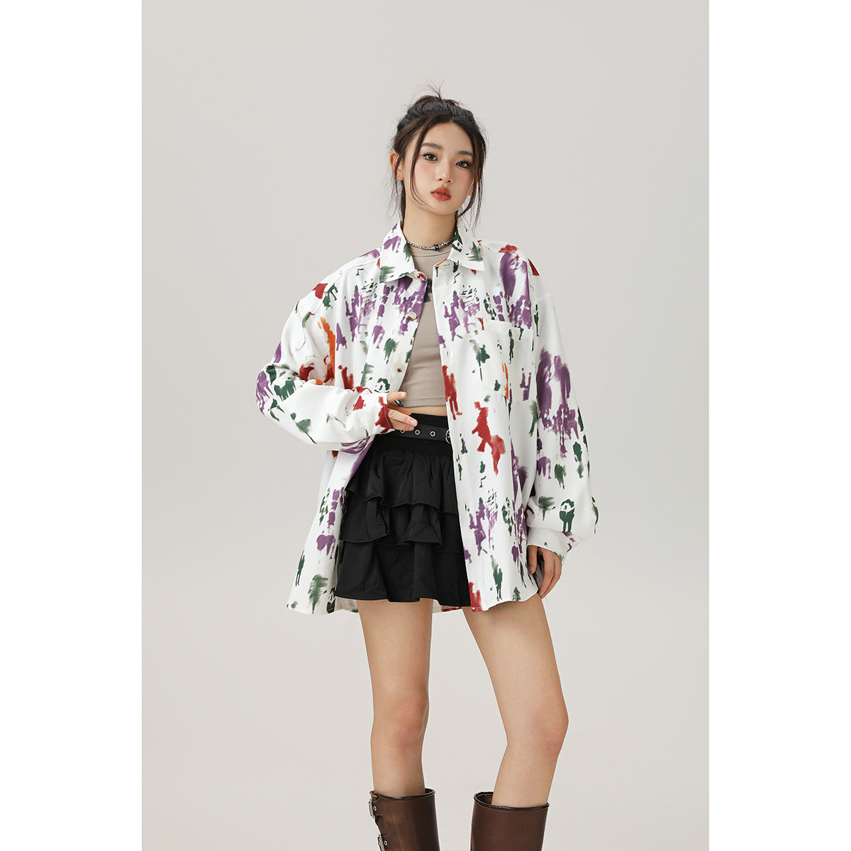 Model wearing an oversized white button-up shirt with colorful abstract prints, a chest pocket and long sleeves.