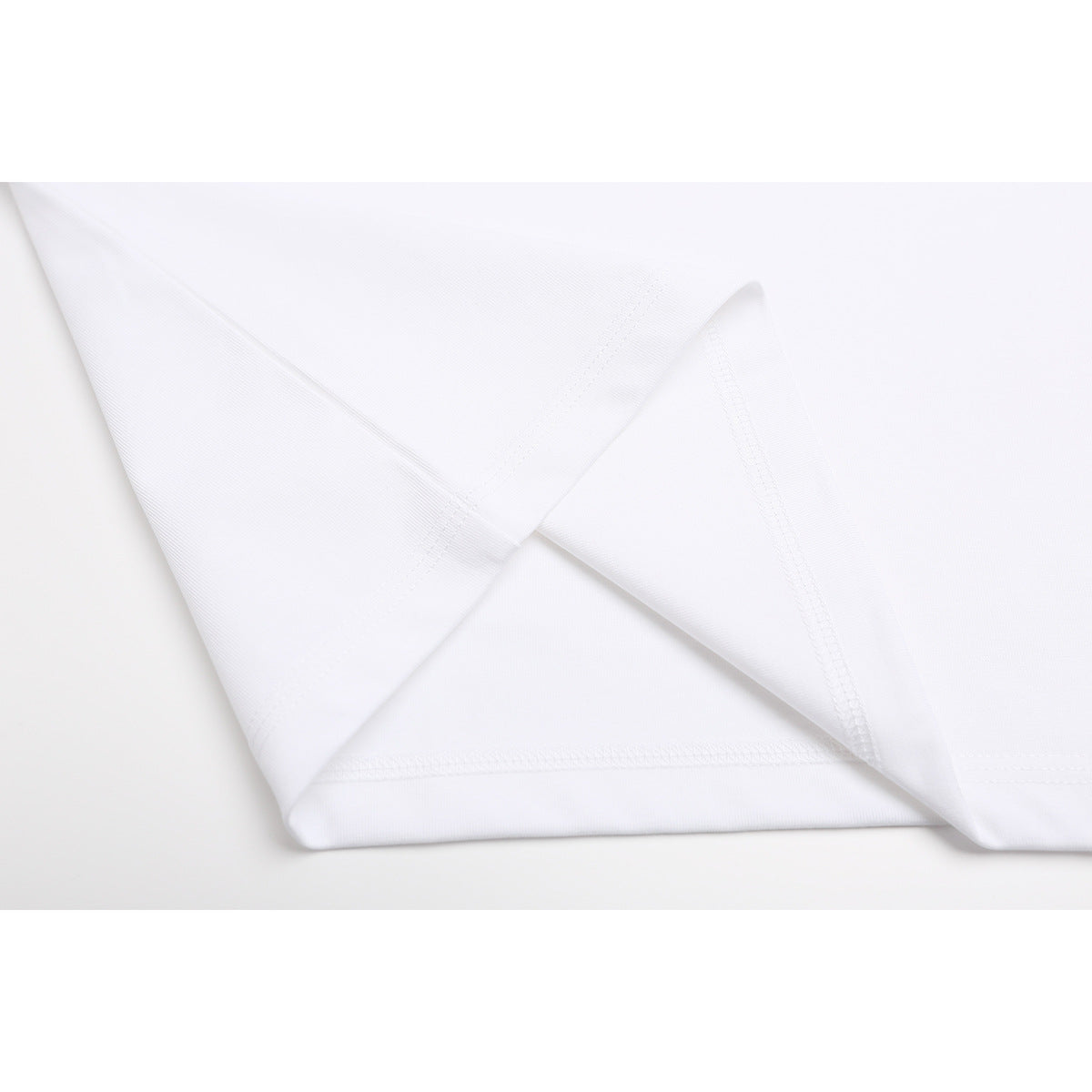 Close-up of the white T-shirt’s folded fabric and stitched hem.