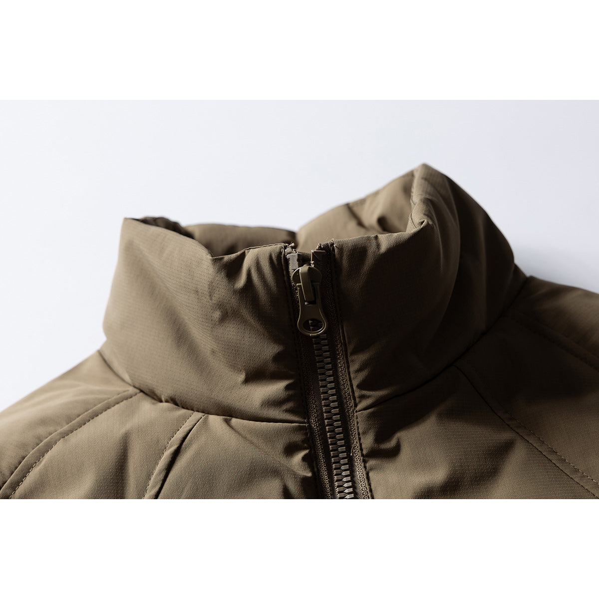 Close-up of an olive-brown padded jacket’s high stand collar and central zipper.