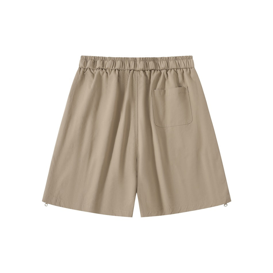 Back view of tan loose shorts with an elastic waistband and a single patch pocket.