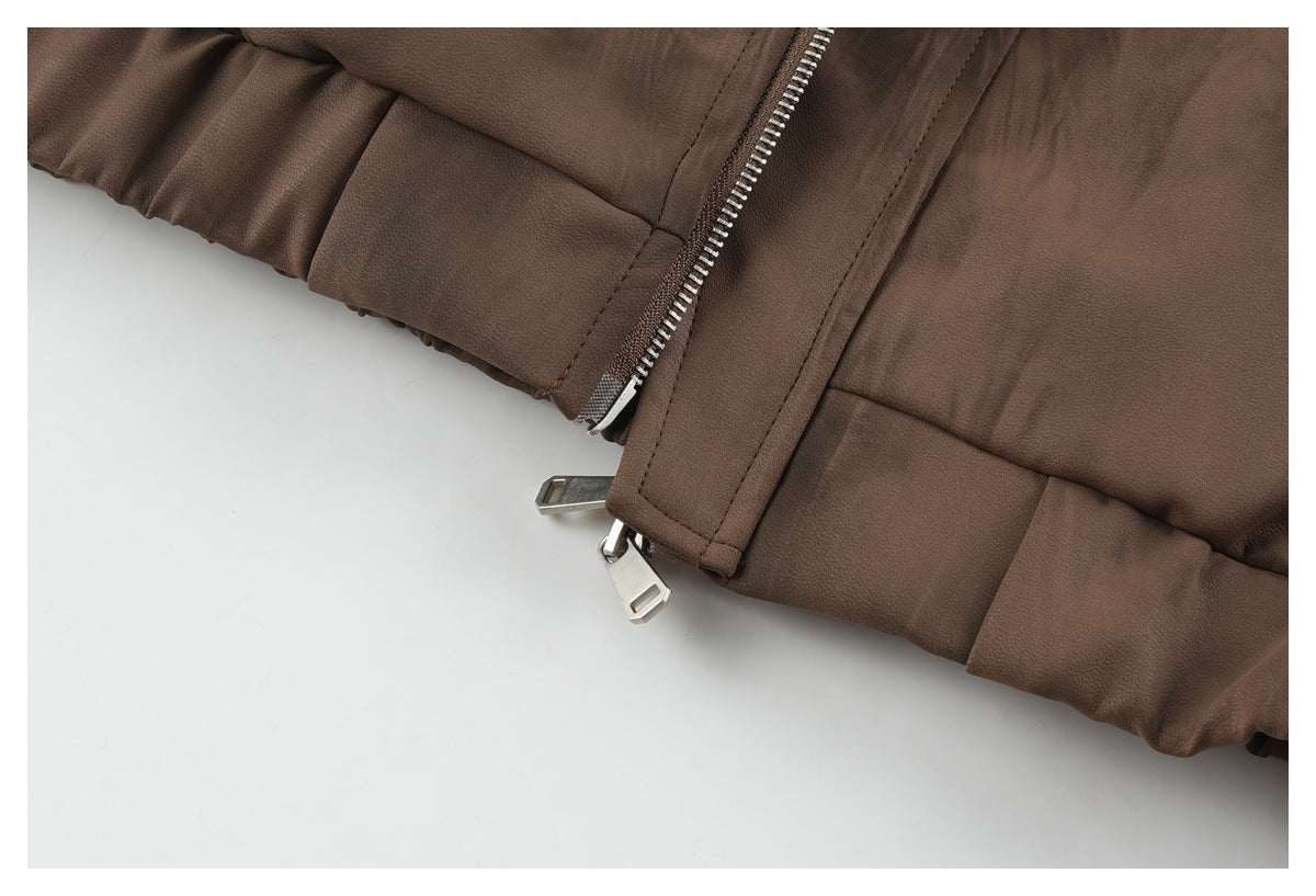 Close-up of a brown jacket hem with a zipper, metal pulls, and gathered edge.