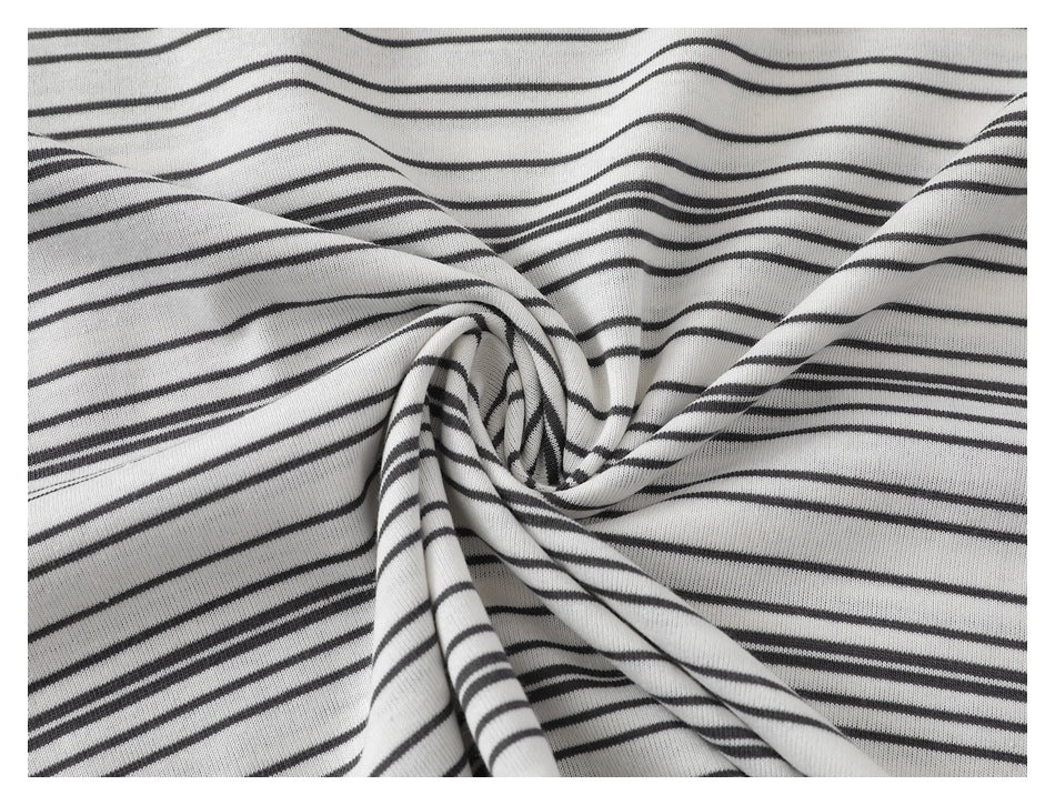 Close-up of white fabric with thin black stripes gathered into a spiral fold.