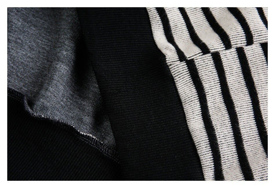 Close-up of the inside seam, gray reverse fabric, and black ribbed trim beside striped knit fabric.