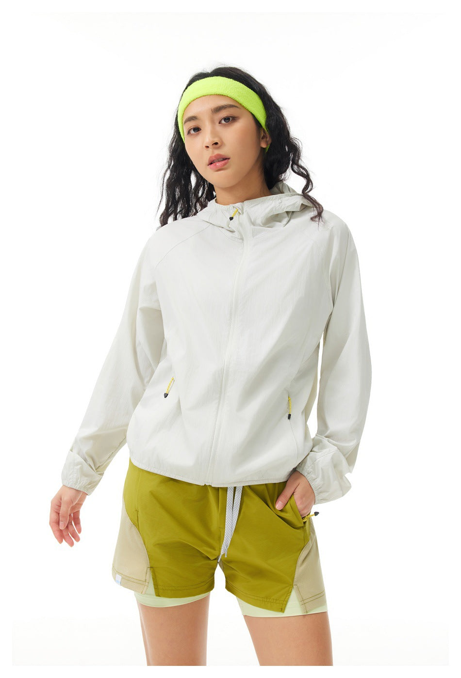 Closer front view of a model in an off-white hooded jacket and olive layered shorts.