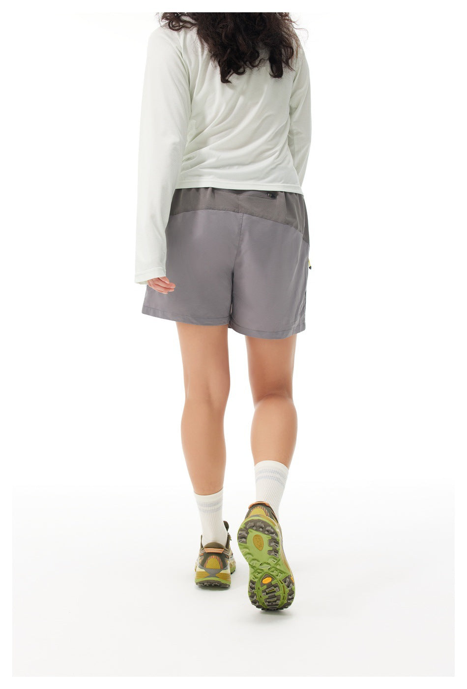 Back view of a model wearing a gray athletic skort with a darker waistband panel and short-length cut.