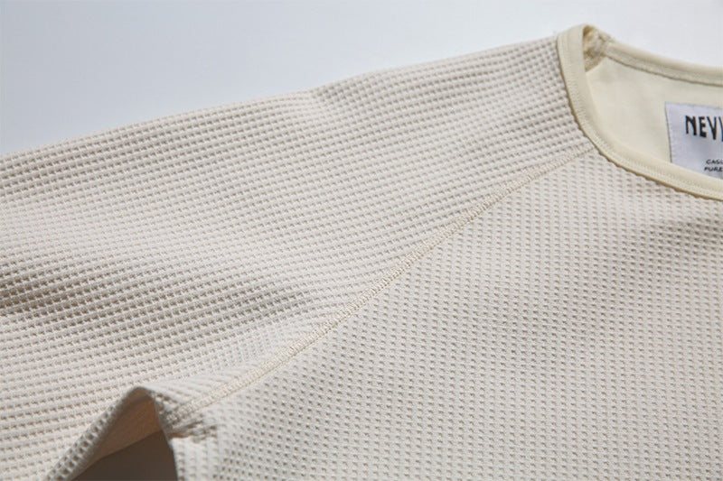 Close-up of the cream waffle-knit shoulder, raglan seam, and neckline.