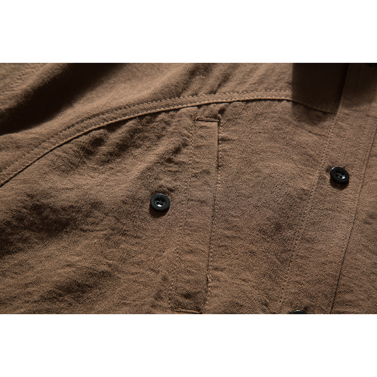 Close-up of the brown shirt's chest pocket, stitching, and black buttons.