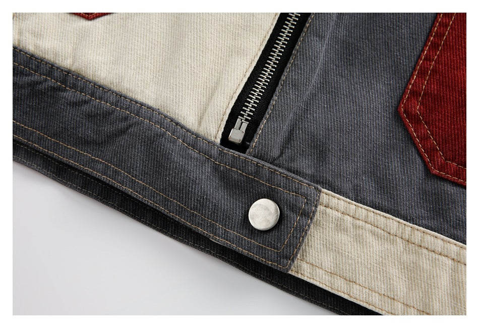 Close-up of a color-block jacket showing a black zipper, metal snap, and charcoal and cream panels.