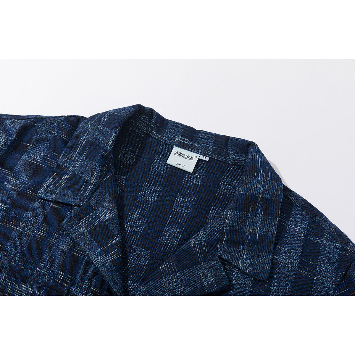 Close-up of a navy plaid shirt collar and lapel with a visible neck label.