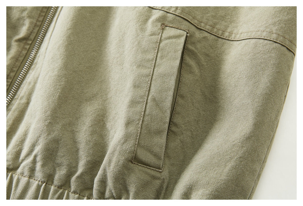 Close-up of a narrow rectangular pocket on the sleeve of an olive khaki jacket.