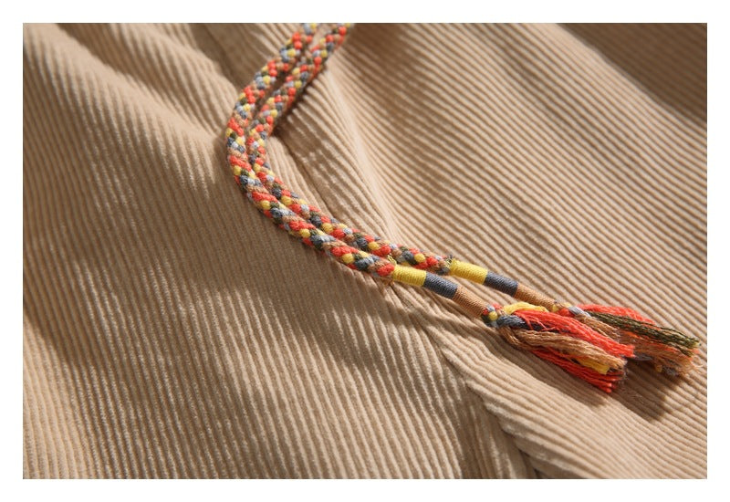 Close-up of a multicolored braided drawstring and tassel on tan corduroy shorts.