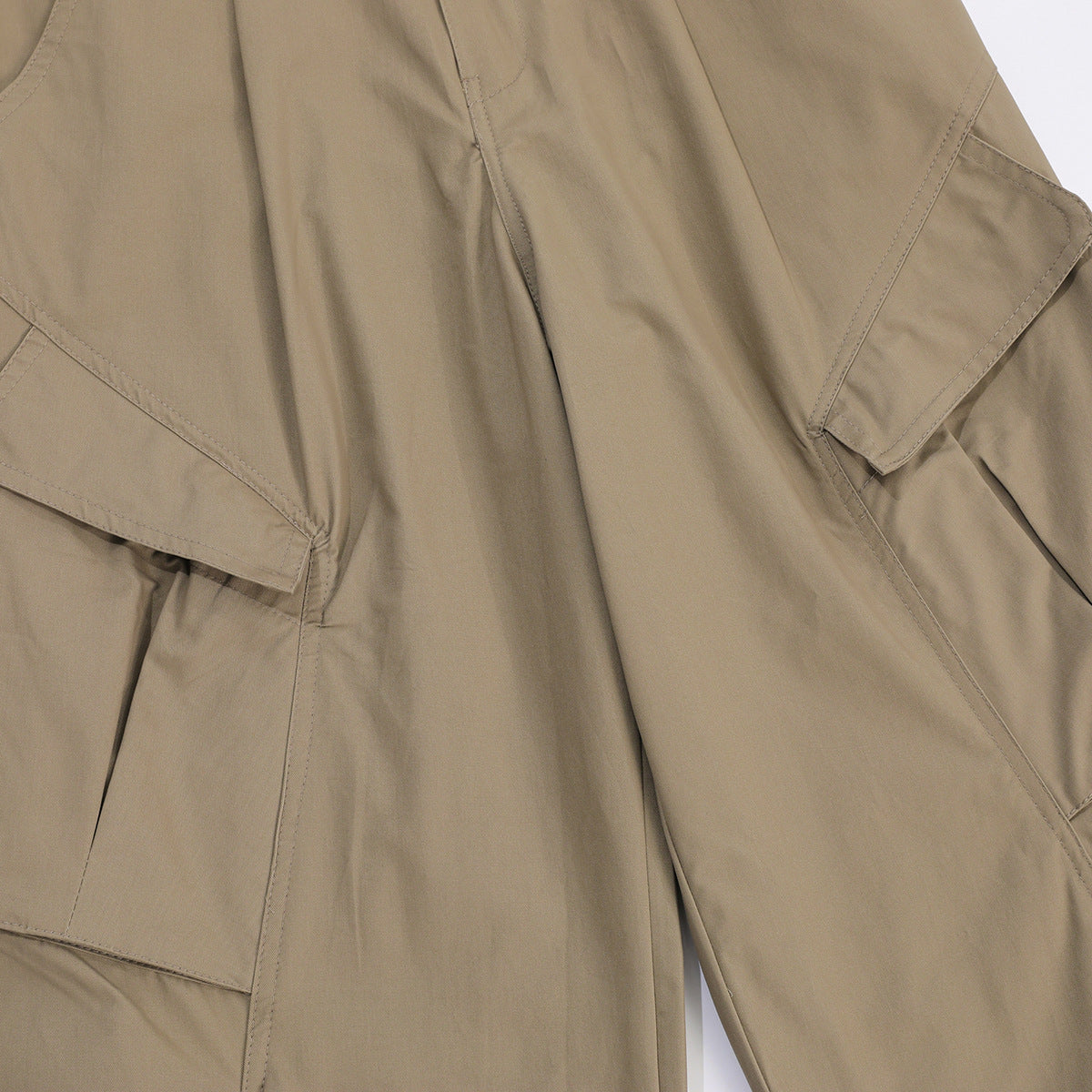 Close-up of tan cargo pants with large flap cargo pockets and stitched seams.