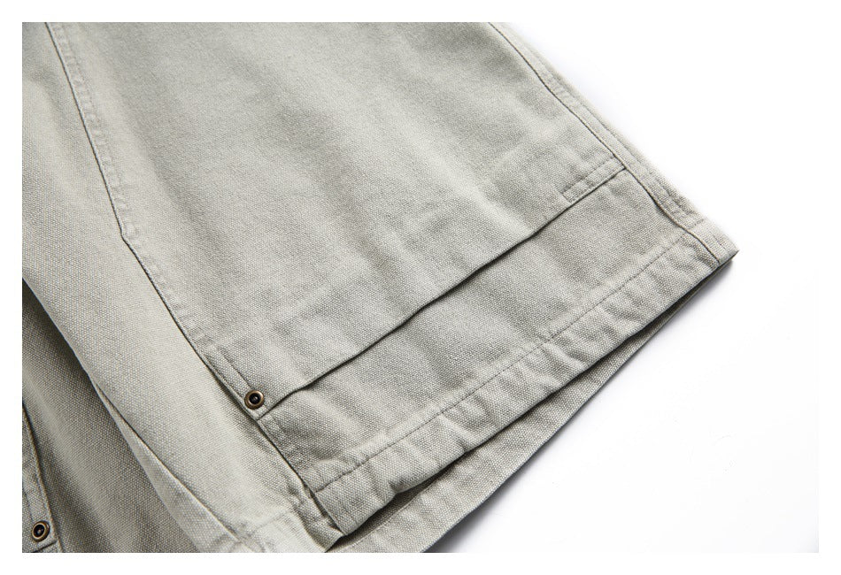 Close-up of the stitched hem and edge of light gray-beige bottoms, with a metal rivet.