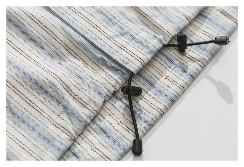 Close-up of black drawcord toggles on cream fabric with blue and brown stripes.
