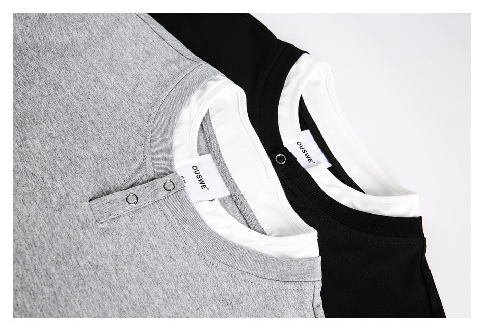 Close-up of gray and black tops showing layered white necklines, snap-button plackets, and inside labels.